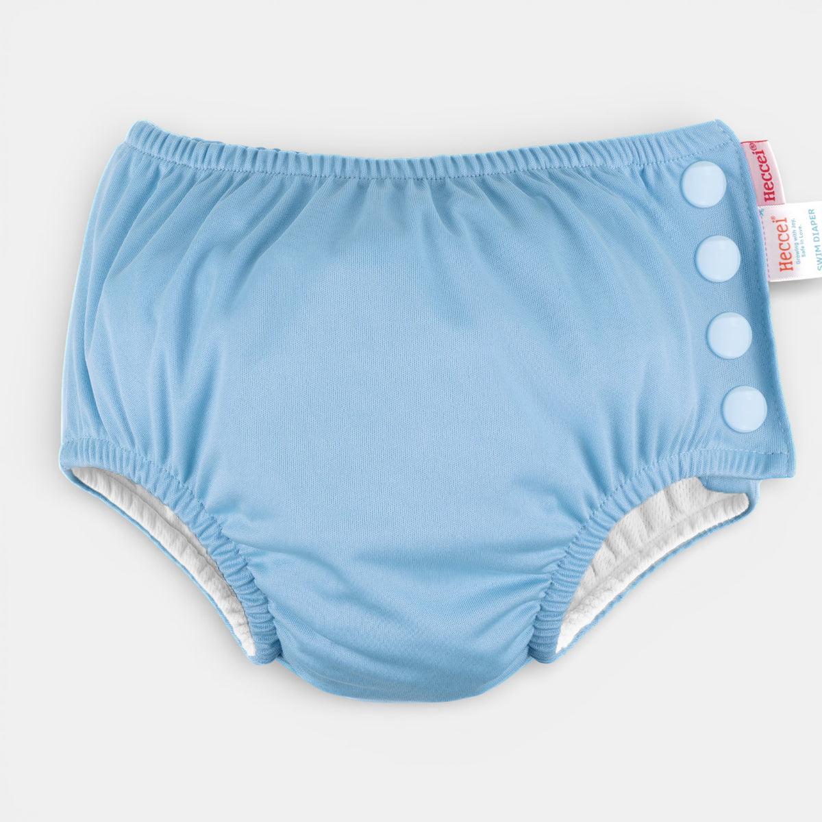 HECCEI reusable swim diaper in blue, with soft elastic waist and legs, quick-dry fabric on a poolside towel.